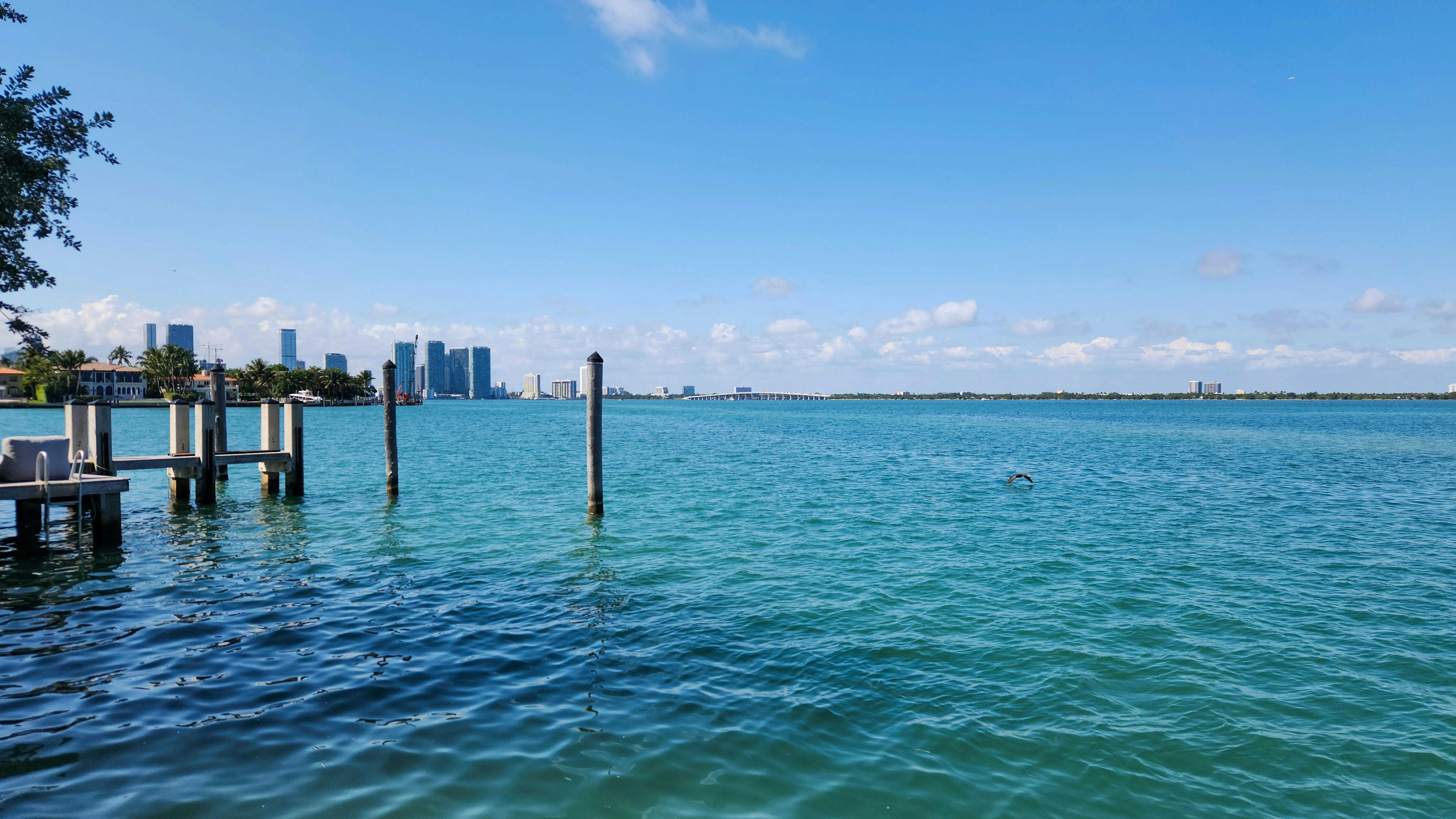 Small white boat cutting across Biscayne Bay with the Edgewater tower skyline rising on the far shore